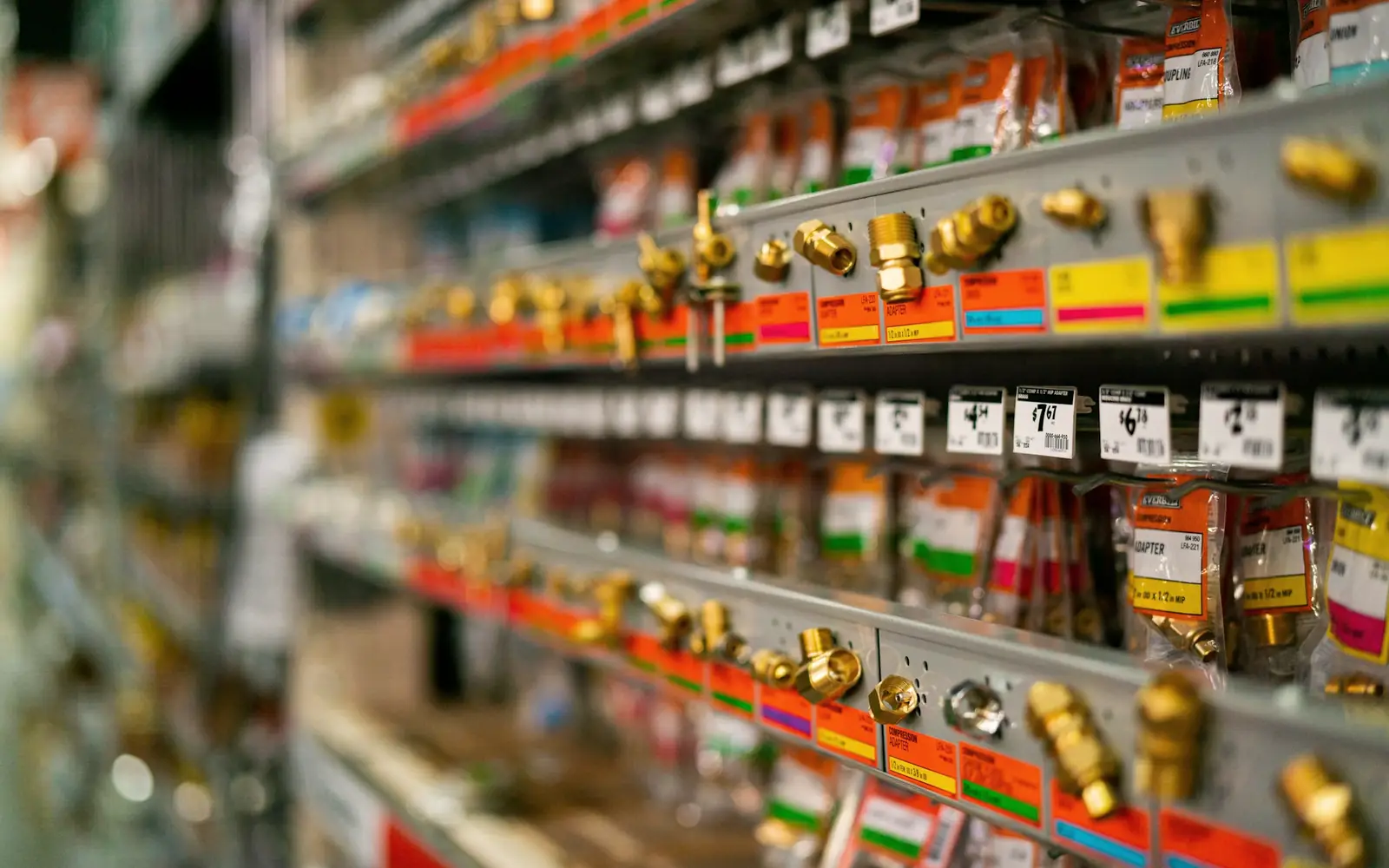 Hardware store shelves of brass fittings with colour-coded labels