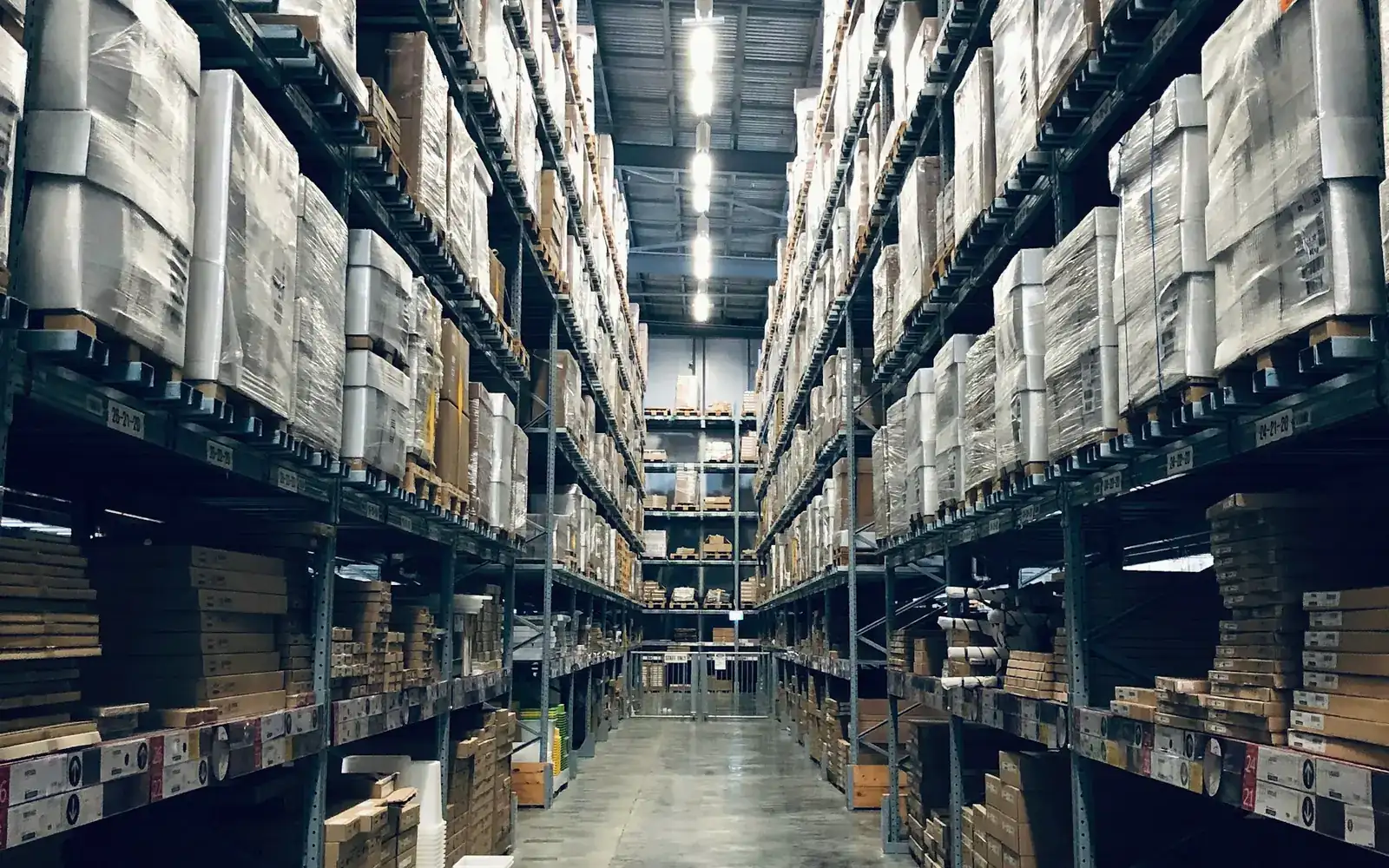 A tall warehouse aisle with high racking full of boxed stock