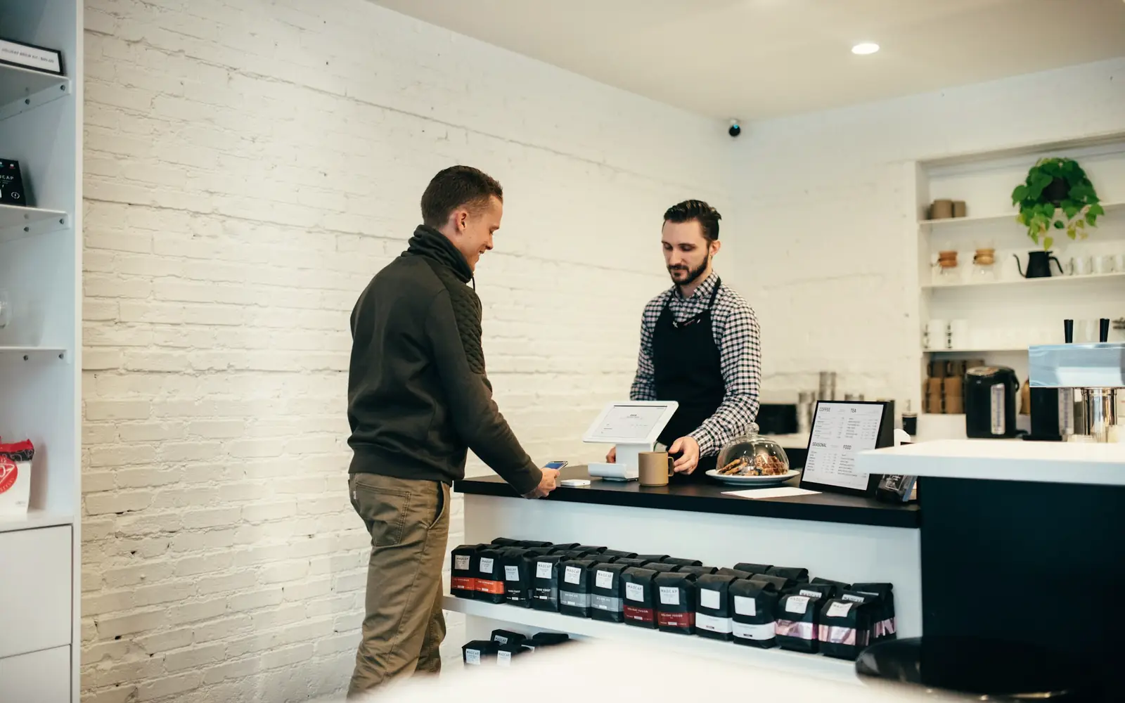 A customer paying a staff member at the counter of a bright shop