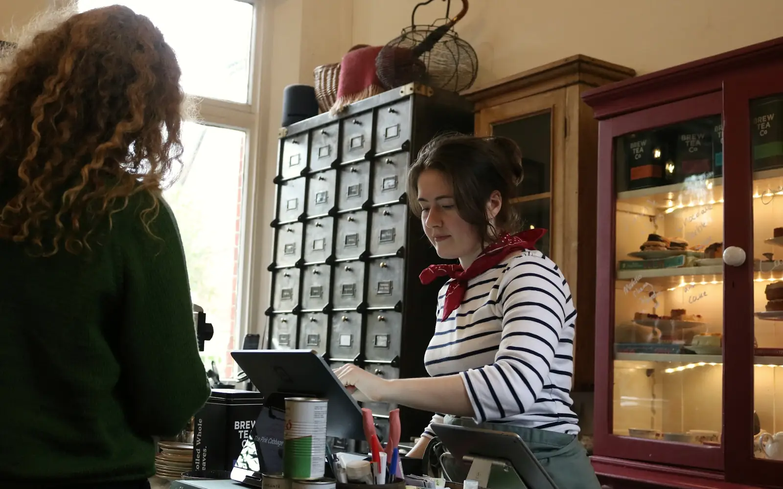 A cashier serving a customer at the counter of a small shop