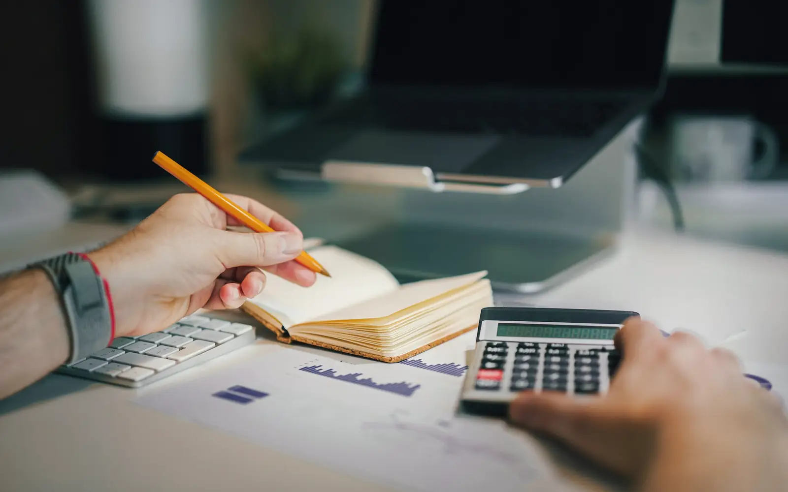 A person working through figures with a calculator and a notebook