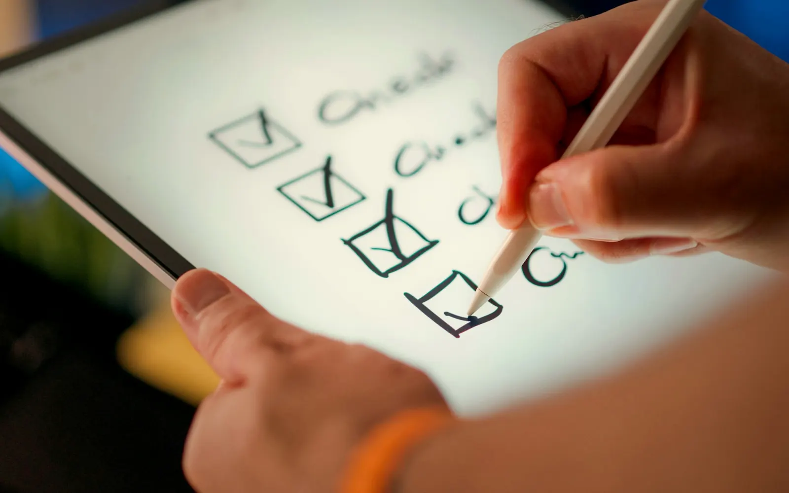 A hand ticking off items on a checklist on a tablet
