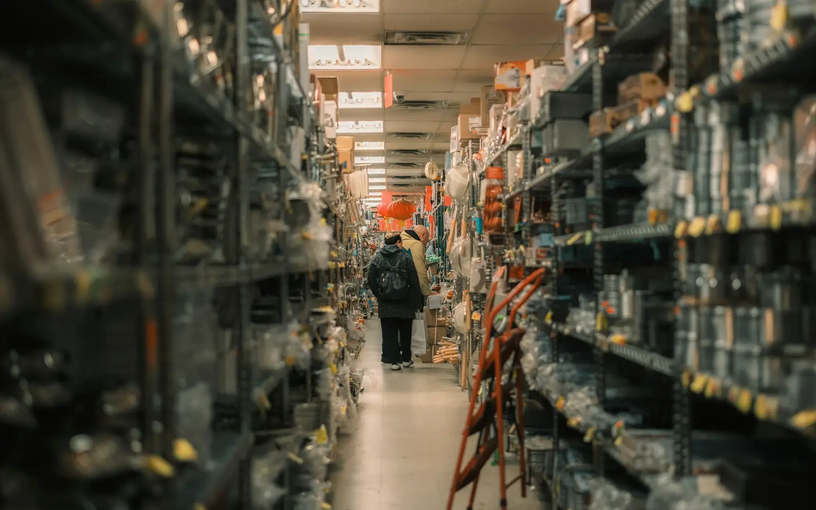 A long stockroom aisle of packed shelving with a person in the distance